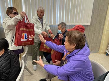 Members of the North District Elderly Committee present lucky bags to the elderly. 1